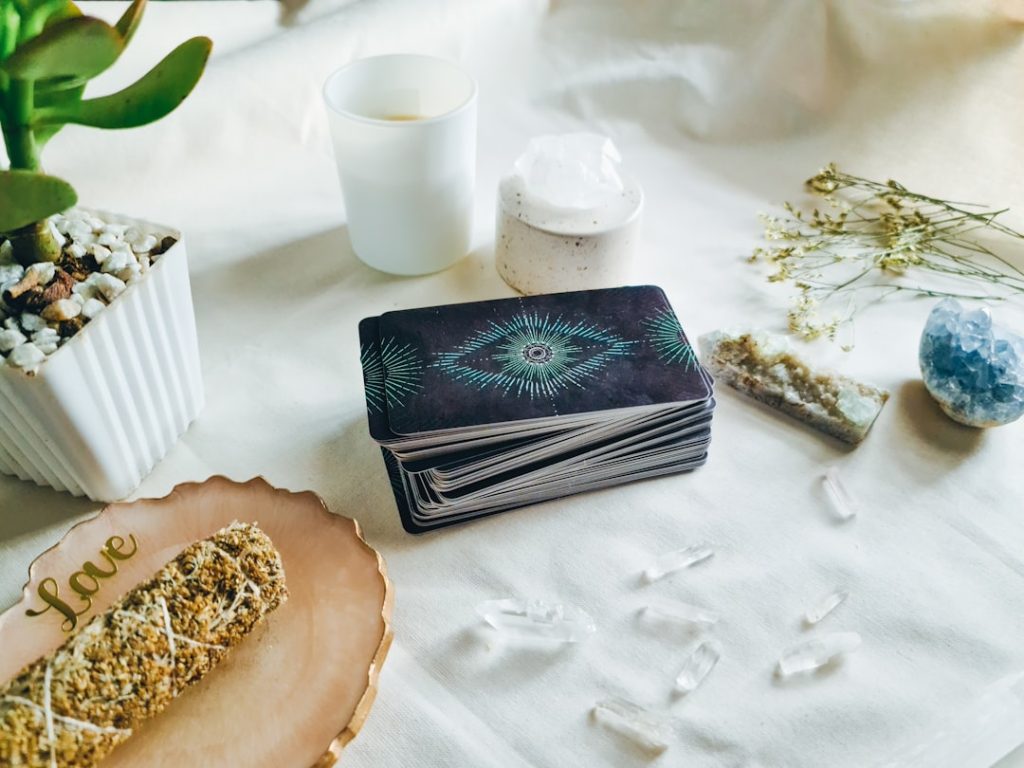 a-table-topped-with-a-stack-of-books-next-to-a-plant-eux74j-ipxw Tarot Cards, Crystals, and Cedar Smudge.