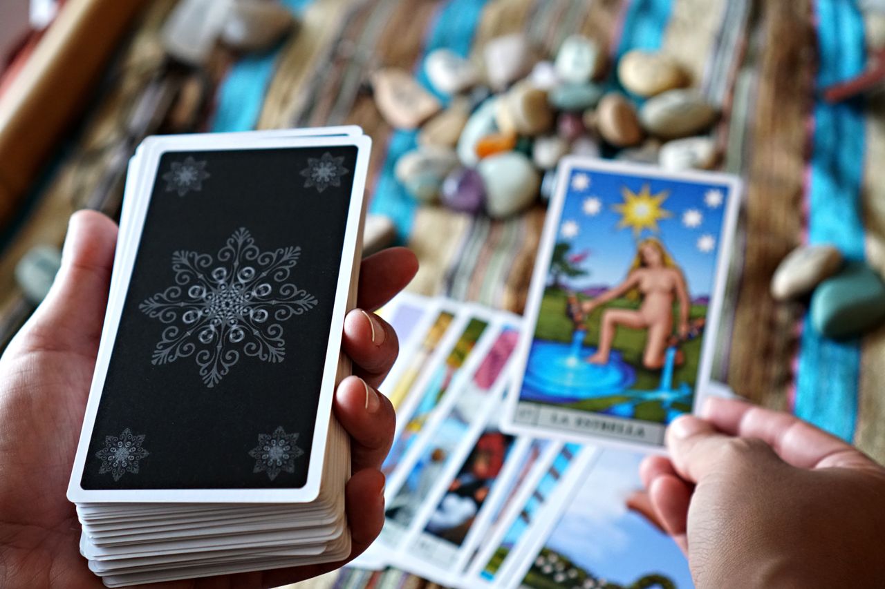 A close-up view of hands holding tarot cards, ideal for fortune telling or divination concepts.